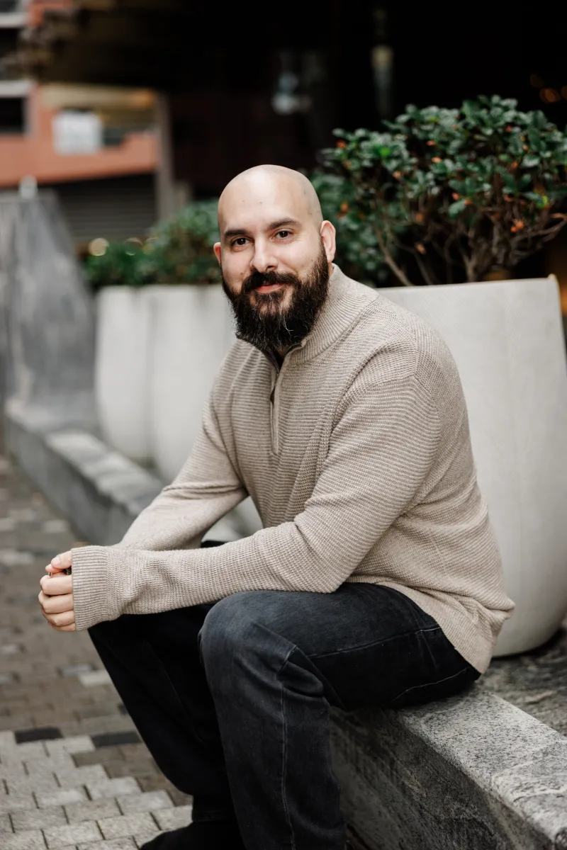 Rob Alford, seated outdoors in a beige quarter-zip sweater, smiling at the camera.